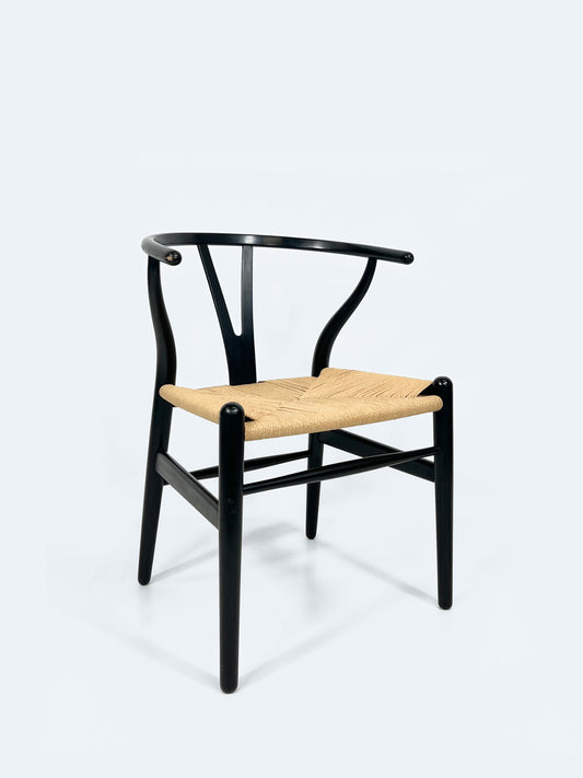 Der „Wishbone Chair“ mit einem deckend schwarz lackierten Holzrahmen und einer Sitzfläche aus Papierkordelgeflecht.